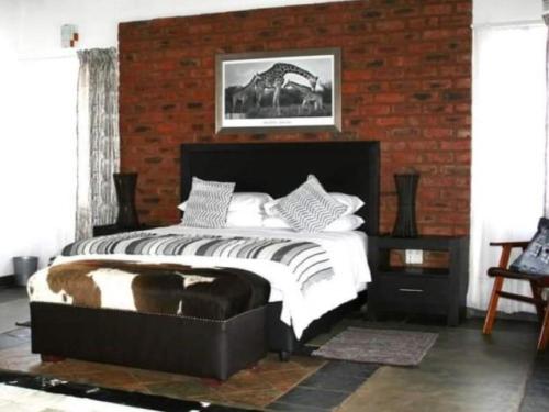 a bedroom with a large bed and a brick wall at Arotin Game Lodge in Brits