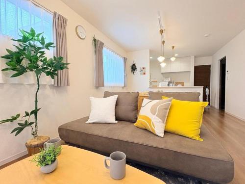 a living room with a couch with yellow pillows at HIRO HOUSE Marugame - 丸亀駅徒歩5分 in Marugame