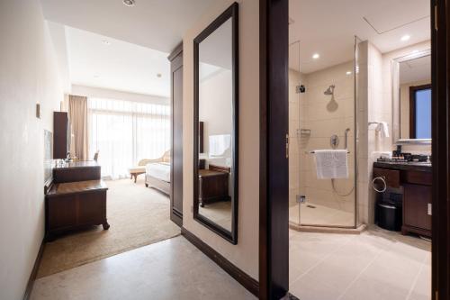 a bathroom with a walk in shower and a mirror at Tang Palace Hotel in Accra