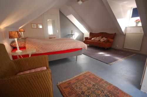 um quarto no sótão com uma cama e um sofá em Het Molenaarshuis em Thorn