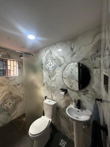 a bathroom with a toilet and a sink and a mirror at Hope Apartments Surulere in Lagos