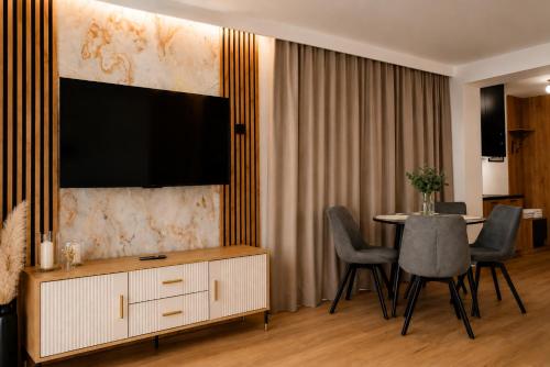 a living room with a tv and a table with chairs at Ruciane Residence in Ruciane-Nida