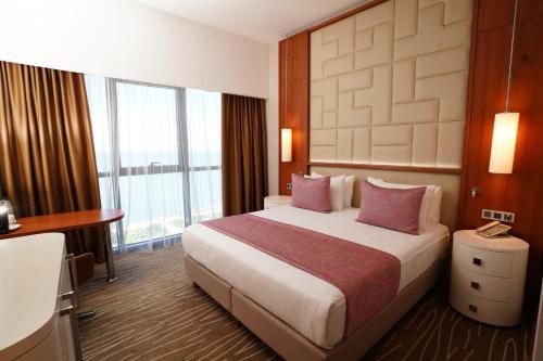 a hotel room with a large bed with pink pillows at Grand Bellagio Hotel Batumi in Batumi