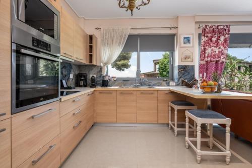 a kitchen with wooden cabinets and a large window at Celeste Sea View Home with Jacuzzi and BBQ in Psalidi