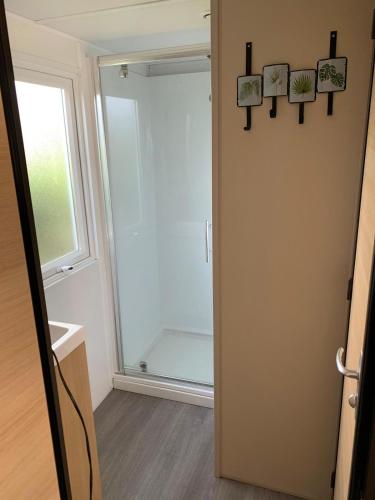 a bathroom with a glass door and a window at Mobilhome avec piscine in Ruoms