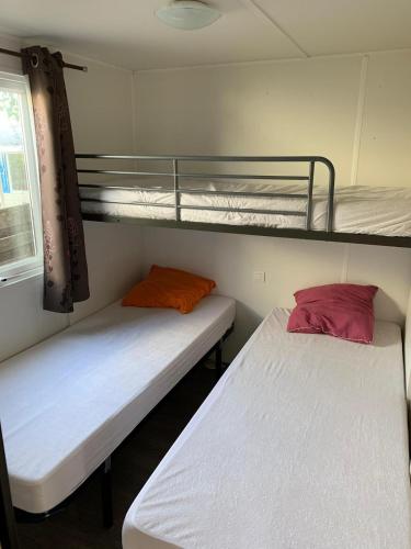 two beds in a room with two bunk beds at Mobilhome avec piscine in Ruoms