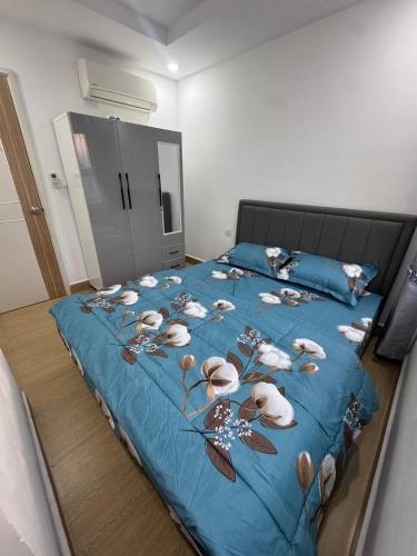 a bed with a blue blanket with flowers on it at L Residence 2 BTB in Phnom Penh