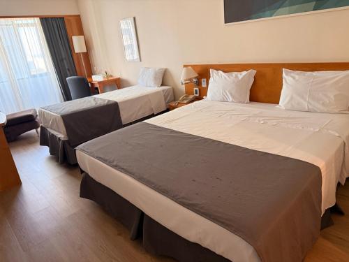 a hotel room with two beds and a chair at Hotel & Residence Alphaville in Barueri