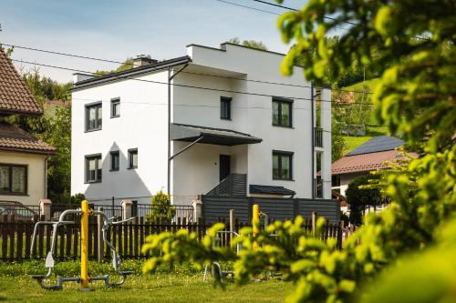a white building with a fence in front of it at Cetyna Retreat - Dom w Beskidzie Sądeckim, 8 osób, szlaki, cisza, EV in Rytro