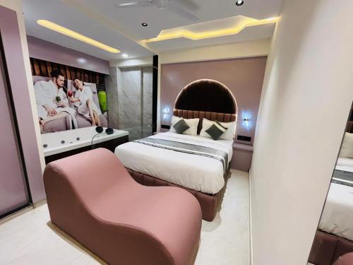 a bedroom with a large bed and a pink chair at Hotel Pacific Empire in Ahmedabad