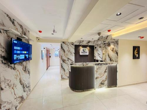 a lobby with marble walls and a tv on a wall at Hotel Pacific Empire in Ahmedabad