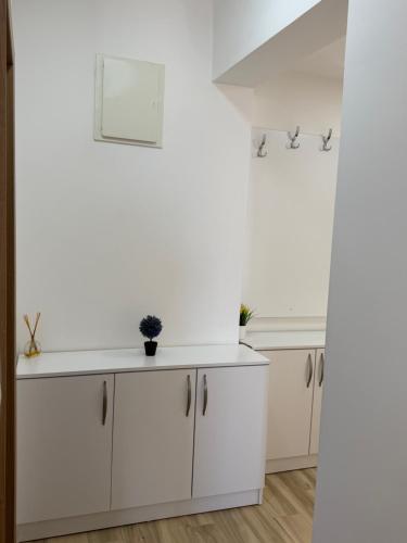 a kitchen with white cabinets and a white wall at Sunrise apartmani in Bar