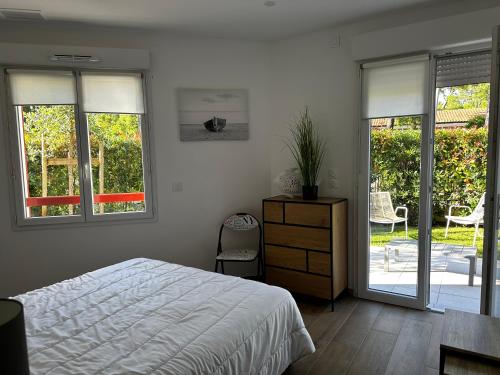a bedroom with a bed and sliding glass doors at Villa Bambous 1 et 2 in Hossegor