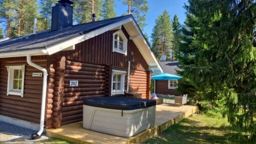 a log cabin with a hot tub on the porch at Honkahimos 7, Pohjois-Huippu, Jämsä in Jämsä