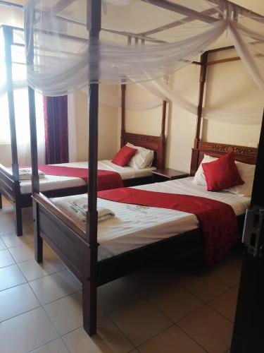 a bedroom with two beds with red pillows at The Folks Inn in Mombasa