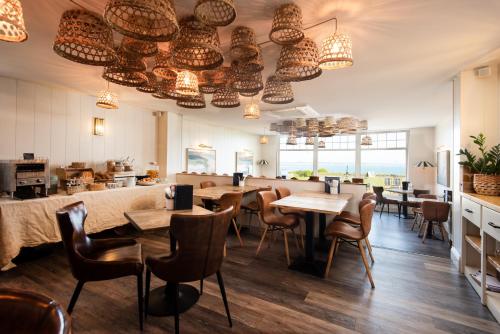 a restaurant with tables and chairs and chandeliers at Beach House Hotel in Seahouses