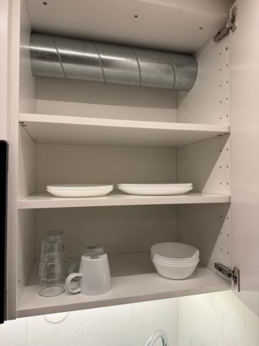 a kitchen with white plates and bowls on shelves at Smart mini apartment with kitchen in Åmot