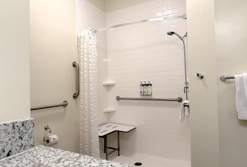 a white bathroom with a shower and a sink at Candlewood Suites - Jacksonville - Mayport by IHG in Jacksonville