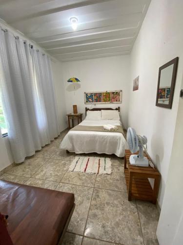 a white bedroom with a bed and a table at Quartos em Tiradentes MG - A Casa Sarará in Tiradentes