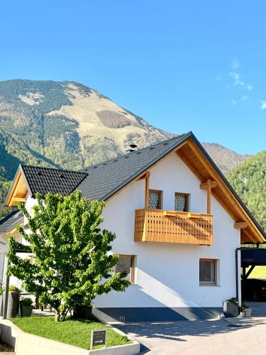 a white house with a balcony and a tree at Slosarjeva Holiday House - Alpine View & Modern Comfort in Preddvor