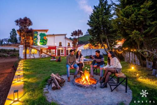 a group of people sitting around a fire pit at Zostel Ooty, Pudumund in Ooty