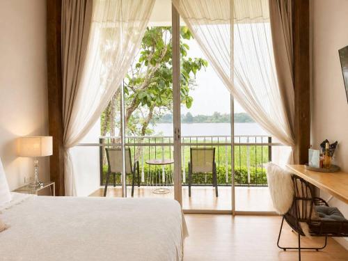 ein Schlafzimmer mit einem Bett und einem großen Fenster in der Unterkunft White Wall Riverfront Hotel in Kamphaeng Phet