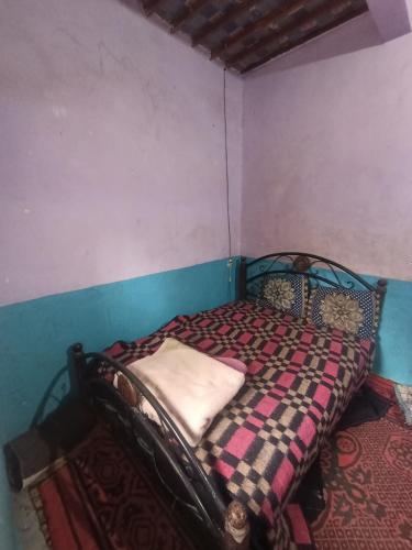 a small bedroom with a bed with a checkered blanket at dar elkarzabi in Zagora