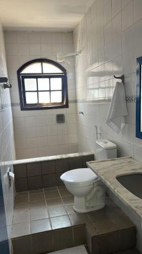 a bathroom with a toilet and a tub and a sink at Santorini Suítes in Tamandaré