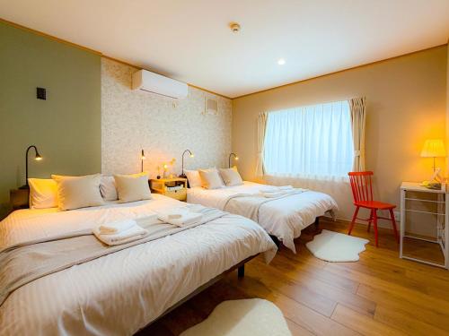 a hotel room with two beds and a red chair at Shirakaba in Otaru