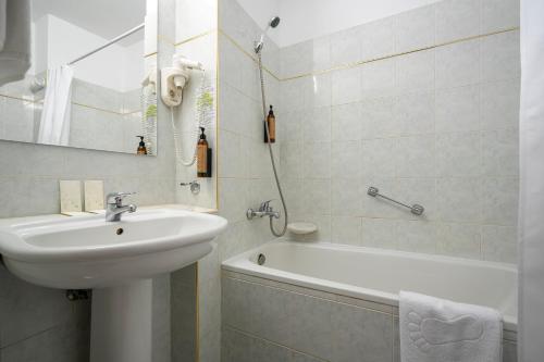 a white bathroom with a sink and a bath tub at Hotel Belvedere in Cluj-Napoca