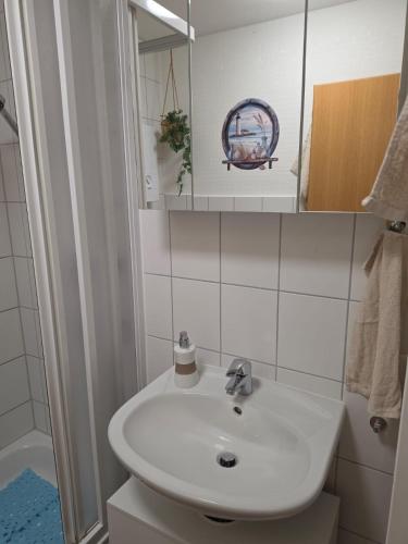 a white bathroom with a sink and a mirror at Ferienwohnung MOIN in Osdorf