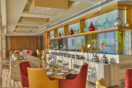 a restaurant with tables and chairs and vases on the wall at Efcee Sarovar Premiere Bhavnagar in Bhavnagar