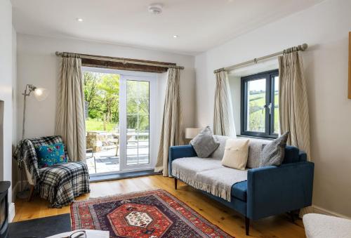 a living room with a blue couch and a chair at Pentreath in Bude