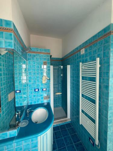 a blue tiled bathroom with a sink and a shower at La Locanda del Mare in Codaruina