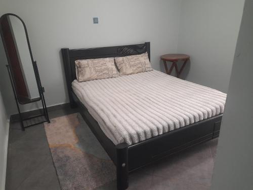 a bed with a black headboard and two pillows at Ebenezer Apartment, Albert Cook Road in Kampala