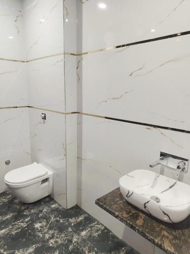 a white bathroom with a toilet and a sink at Hotel Kashi Bliss in Varanasi