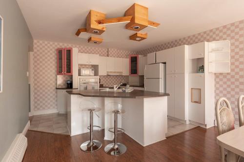 a kitchen with white cabinets and a kitchen island with stools at #Le80ies - Downtown Rooftop - Free shuttle to ski Mountain in Mont-Tremblant