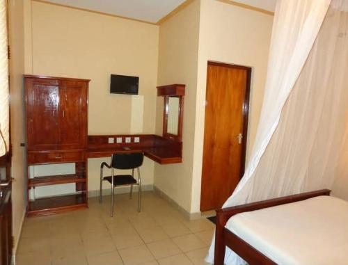 a bedroom with a desk and a bed and a chair at The Folks Inn in Mombasa