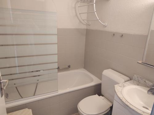 a bathroom with a toilet and a tub and a sink at Westdiep 602 zeezicht, verwarmd binnenzwembad in De Panne