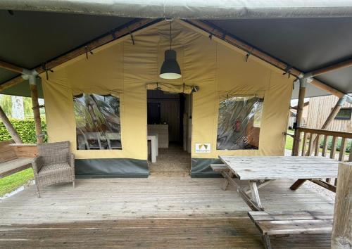 a tent with a wooden deck with a table and a light at Safaritent Ranger Lodge in Kesteren