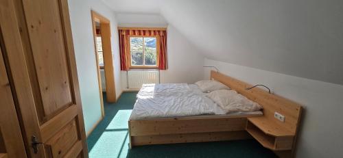 a bedroom with a bed with a wooden frame and a window at Gindlhütte in Tauplitzalm