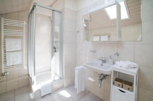 a white bathroom with a shower and a sink at Chalet Lena - Managed by Hotel Gstaaderhof in Gstaad
