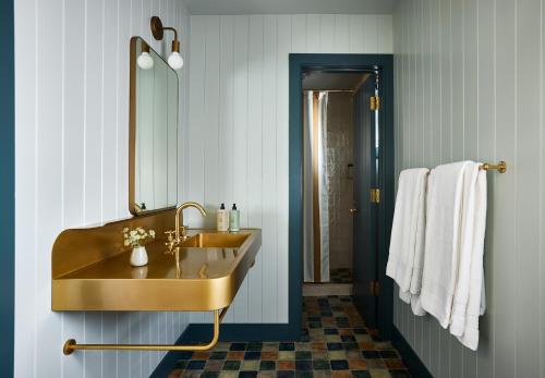a bathroom with a gold sink and a mirror at Hotel Corduroy in Montauk
