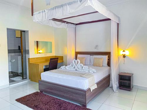 a bedroom with a canopy bed and a bathroom at The Safiya Hotel Apartments in Ukunda