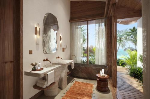 a bathroom with two sinks and a tub and a window at Miraval The Red Sea All Inclusive Adults Only in Ḩanak