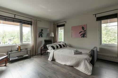 a bedroom with a bed and a couch and windows at Downtown - FREE shuttle to Ski Resort - Ice Rink in Mont-Tremblant