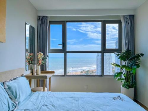 a bedroom with a blue bed and a large window at CĂN HỘ CAO CẤP THE SONG VŨNG TÀU - LUXURY APARTMENT THE SÓNG VŨNG TÀUs in Vung Tau
