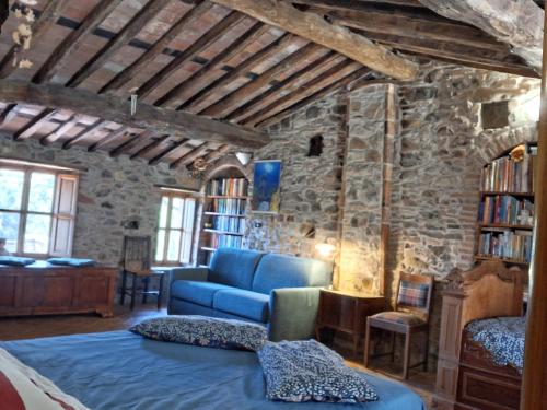 a living room with a blue couch and a stone wall at Attic with balcony at Locanda del Capo in Capannori