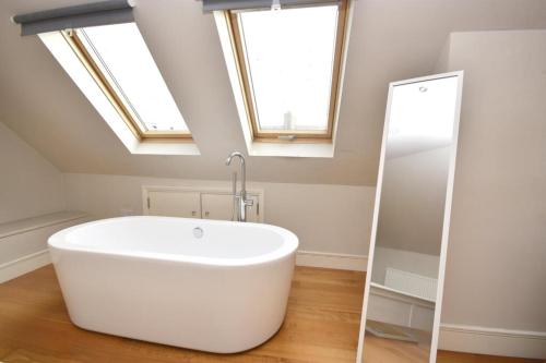 a white bath tub in a bathroom with skylights at Flat 4, 15 Ethelbert Square CT8 8SR in Westgate-on-Sea