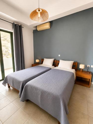 a bedroom with two beds and a large window at 4Seasons Sfakia in Hora Sfakion